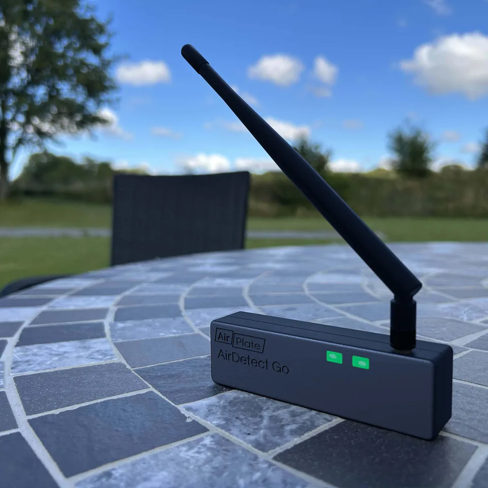 AirDetect Go handheld drone detector with its external antenna up, on an outdoor table